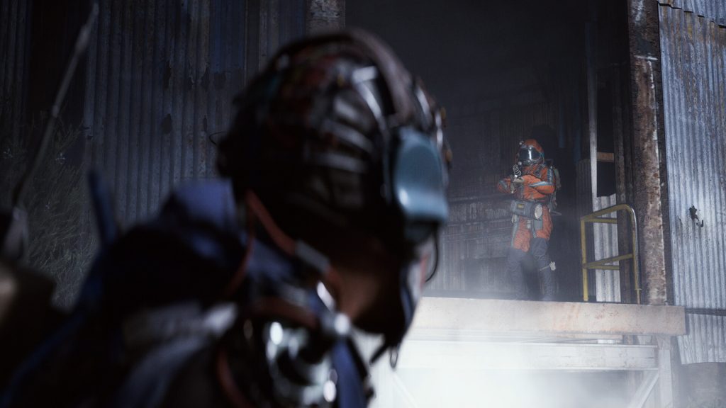 A Raider in a helmet watching another player from cover in a corrugated iron building