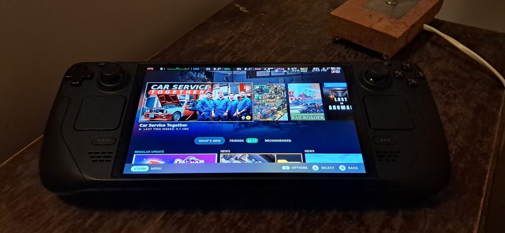 A Steam Deck OLED on a wooden table showing the Steam home screen