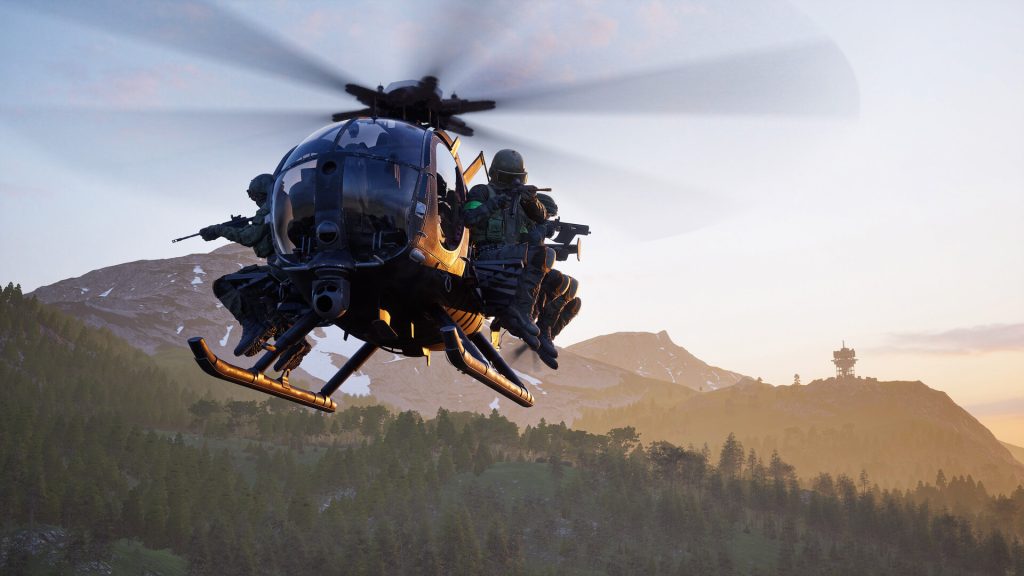 A Wardogs squad riding on the skids of a small helicopter over forested hills